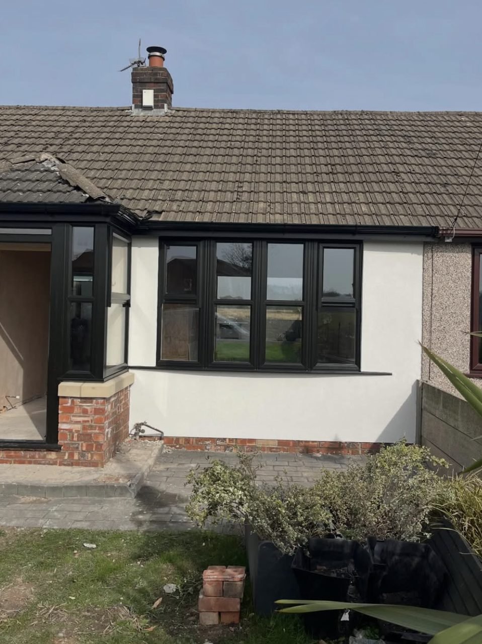 Bungalow front elevation rendered smooth beside untouched pebbledash next door