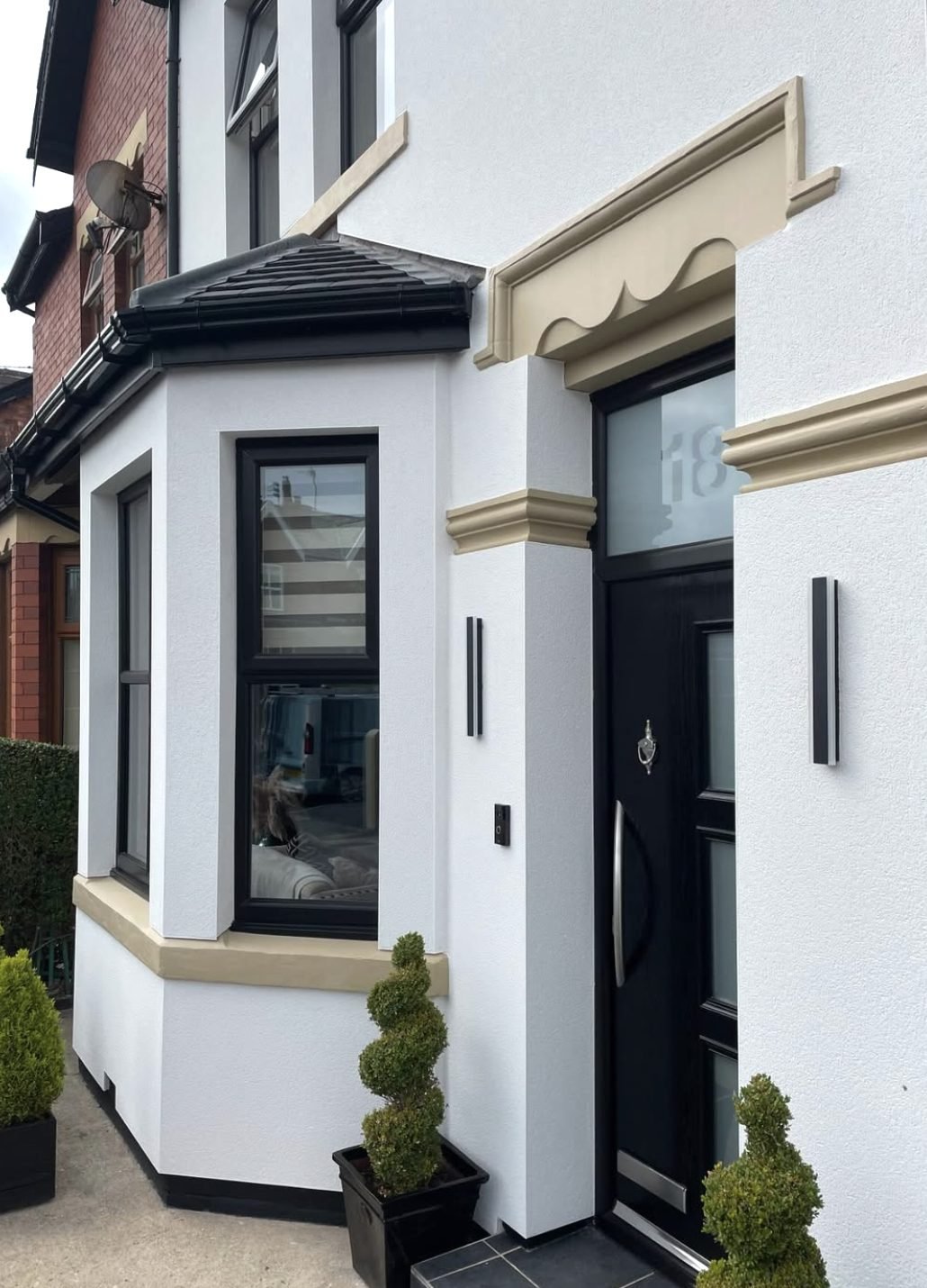 White render worked around an ornate stone door surround and bay window